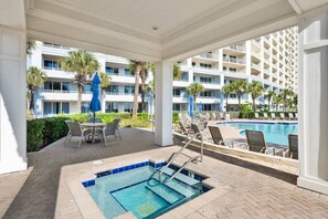 Un espace piscine d’hôtel comprenant un jacuzzi, des chaises longues et une vue sur le bâtiment.