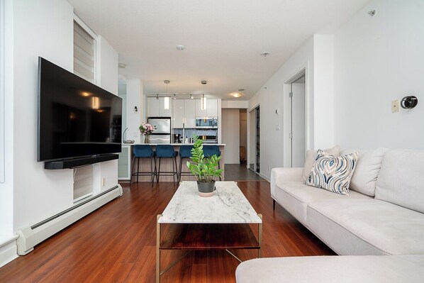 A modern living room with a flat-screen TV, a marble coffee table, and a sofa.