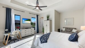 A spacious bedroom with a large bed, a desk, and a television. - New Luxury 5BR Gulf-Access Heated Pool & Spa Home Dock w/ Boat Cleats, Sleeps 13 (Cape Coral)