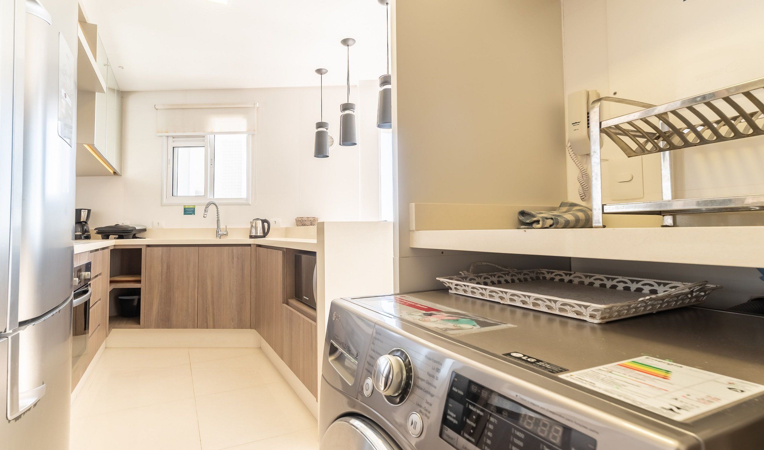 A compact kitchen with a washing machine, a coffee maker, and a kettle.
