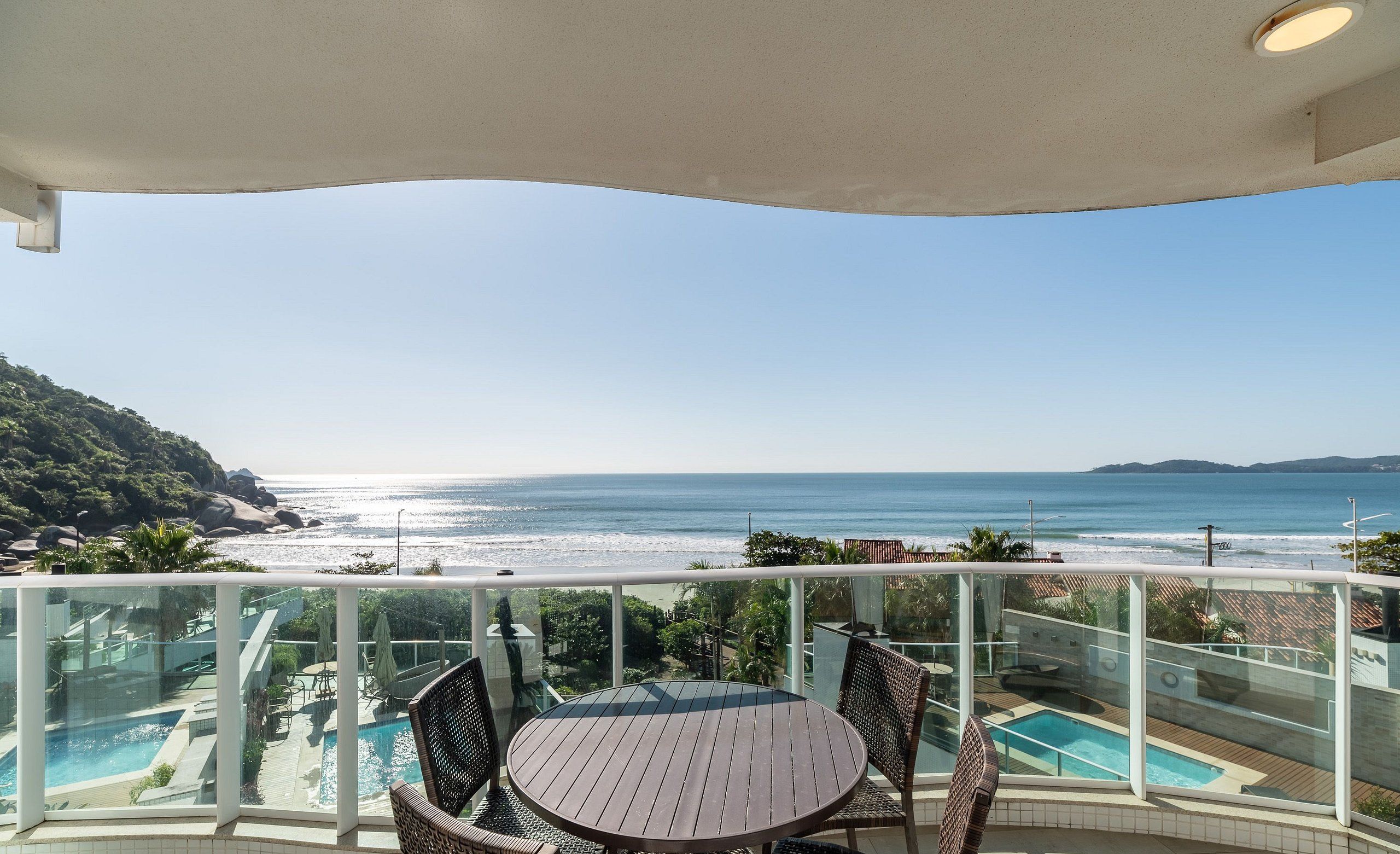 Uma varanda com vista para o oceano, uma piscina e móveis de exterior.