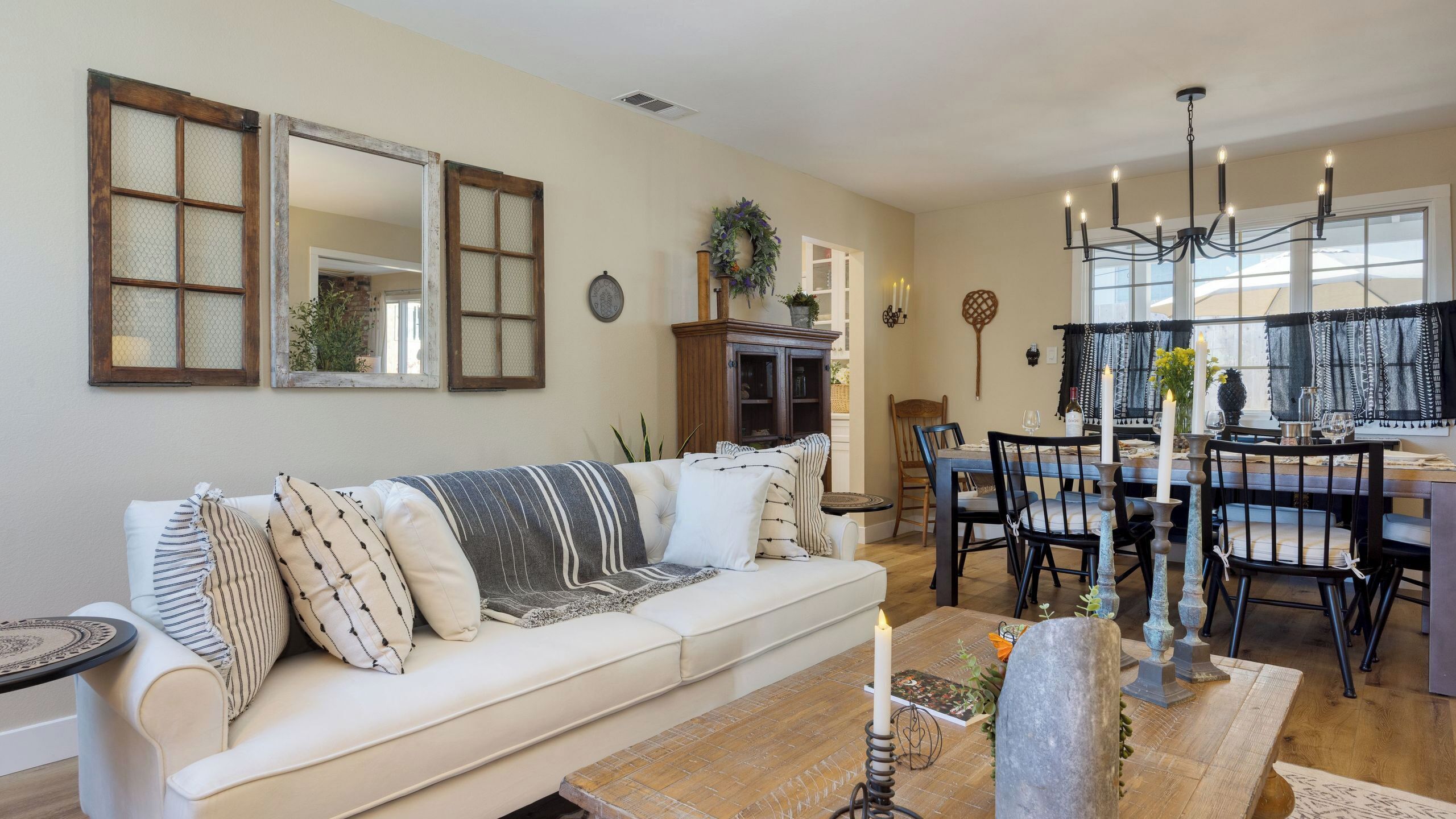 A living room with a sofa, dining table, chairs, and a chandelier.