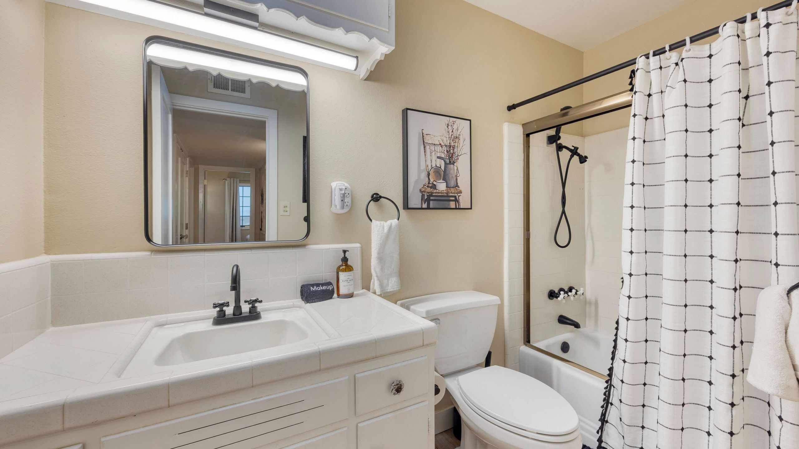 A bathroom with a sink, mirror, toilet, and shower.