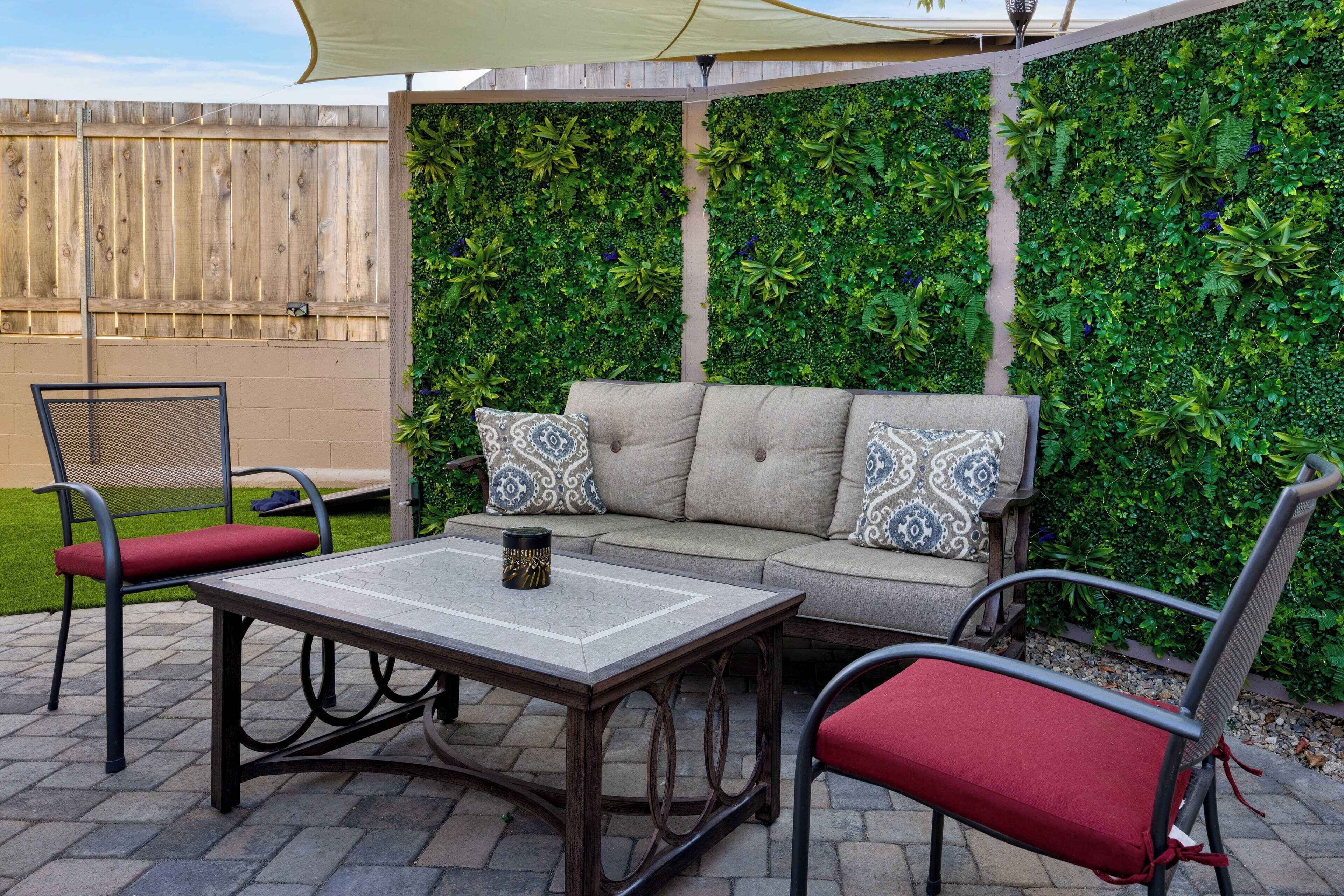 Eine Terrasse im Freien mit einer Couch, zwei Stühlen und einem Tisch.