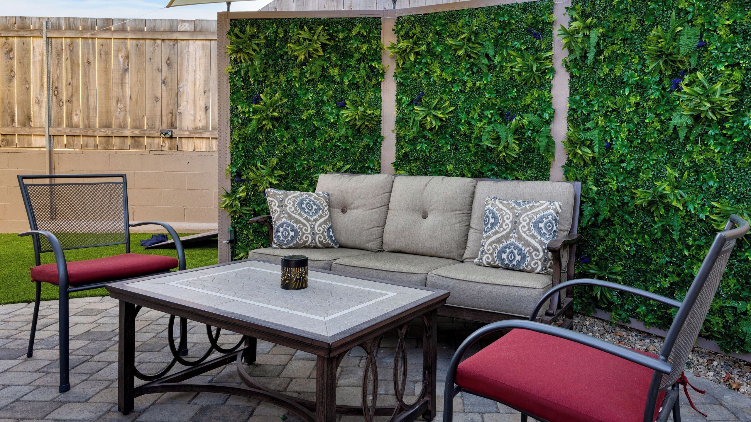A patio with a sofa, two chairs, a table, and a decorative wall.
