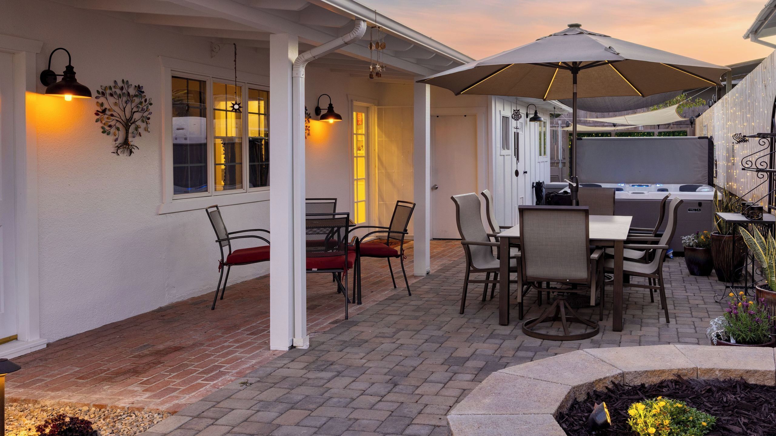 An outdoor patio with a table and chairs, a covered seating area, and a hot tub.