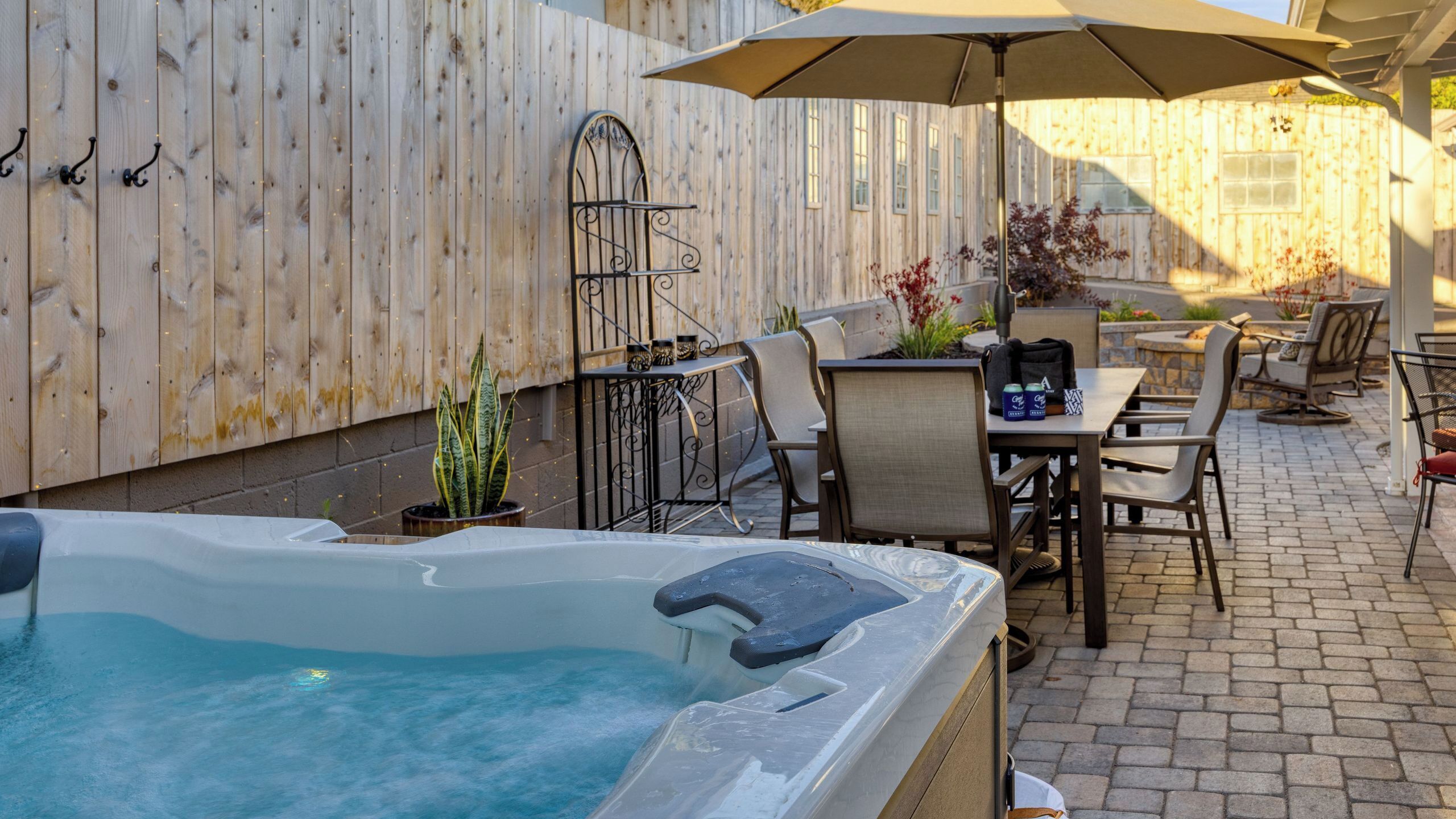 An outdoor patio with a hot tub, patio furniture, and a wooden fence.