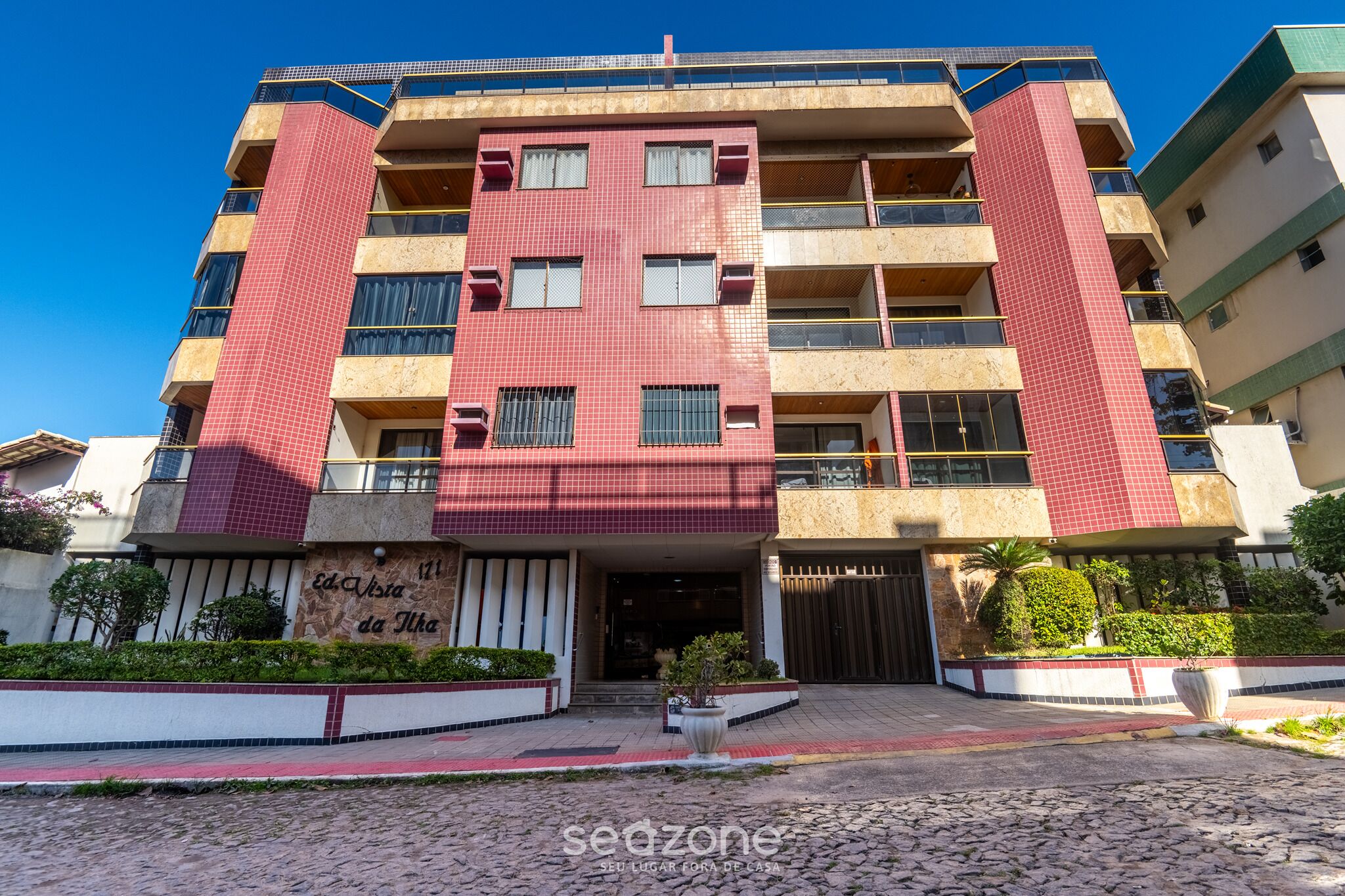 Ein mehrstöckiges Gebäude mit roter Fassade, Balkonen und einem Eingangstor.