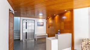 Una hall con soffitto in legno, una reception, una panca e un quadro appeso al muro.