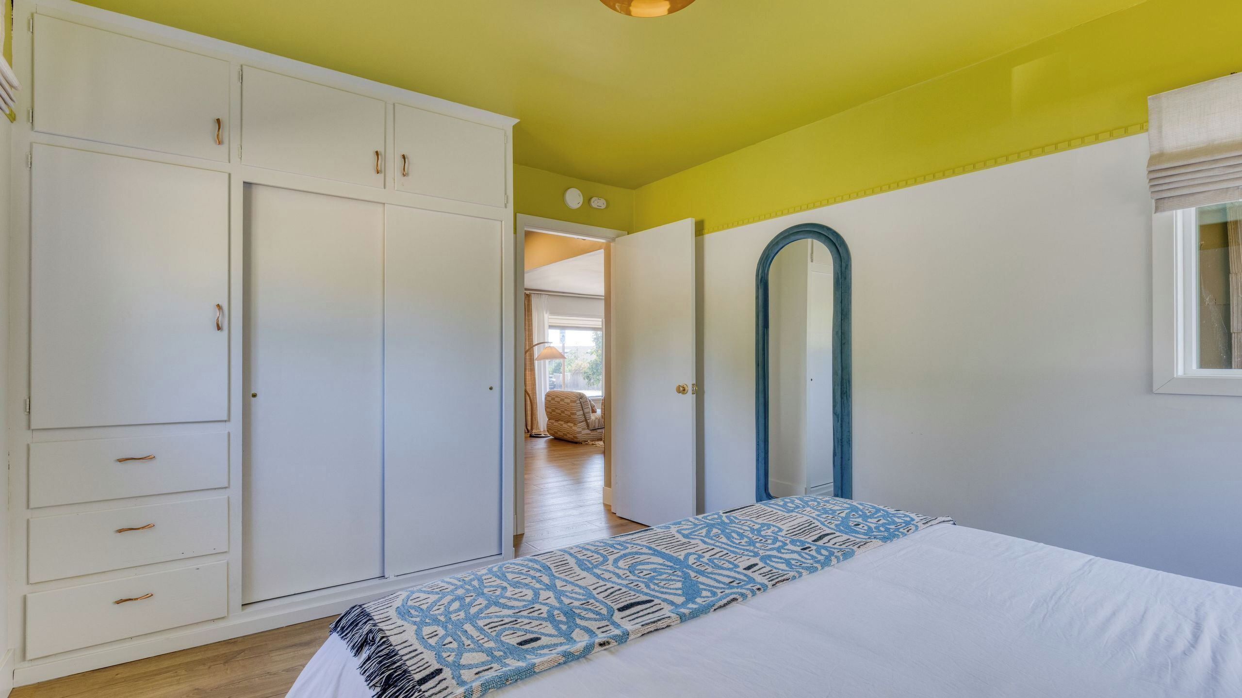 Ein Schlafzimmer mit Bett, Kleiderschrank und einer Tür zu einem anderen Raum.