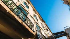 Ein Gebäude mit Balkonen, blauem Himmel und einer Brücke im Hintergrund.