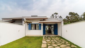 A house with a stone pathway leading to a glass door, a small lawn, and a white fence. - Piece of Greece on the Santa Catarina Coast Umc002 (Barra Velha)