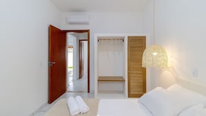 A bedroom with a bed, a wooden door, a walk-in closet, and a wall-mounted lamp. - Piece of Greece on the Santa Catarina Coast Umc002 (Barra Velha)