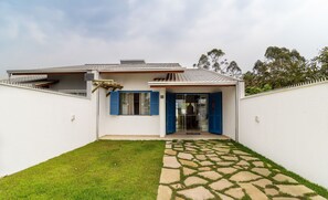 A house with a stone pathway leading to a glass door, a small lawn, and a white fence. - Piece of Greece on the Santa Catarina Coast Umc002 (Barra Velha)