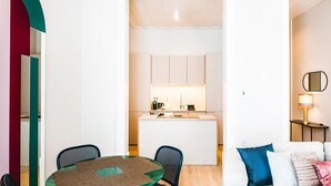 Un espacio habitable compacto con comedor, kitchenette y sofá con almohadones.
