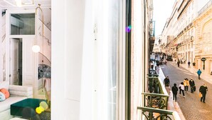 Un interior moderno con un sofá, una mesa de vidrio y vista a una calle concurrida.