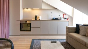 Une cuisine compacte équipée d’un four encastré, d’un évier et d’un plan de travail sur lequel sont disposés divers objets.
