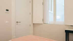 Une chambre à coucher avec un lit, une fenêtre, une porte et une petite table.