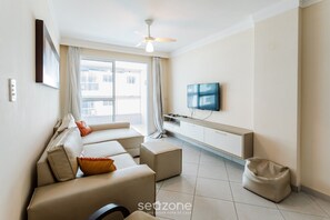 Un salon moderne avec un ensemble de canapés, un téléviseur fixé au mur et un ventilateur de plafond.