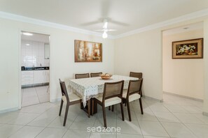 Un coin repas avec une table dressée pour six personnes, un ventilateur de plafond et des œuvres d’art accrochées aux murs.