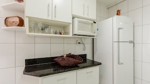 A kitchen with white cabinets, a microwave, and a refrigerator.