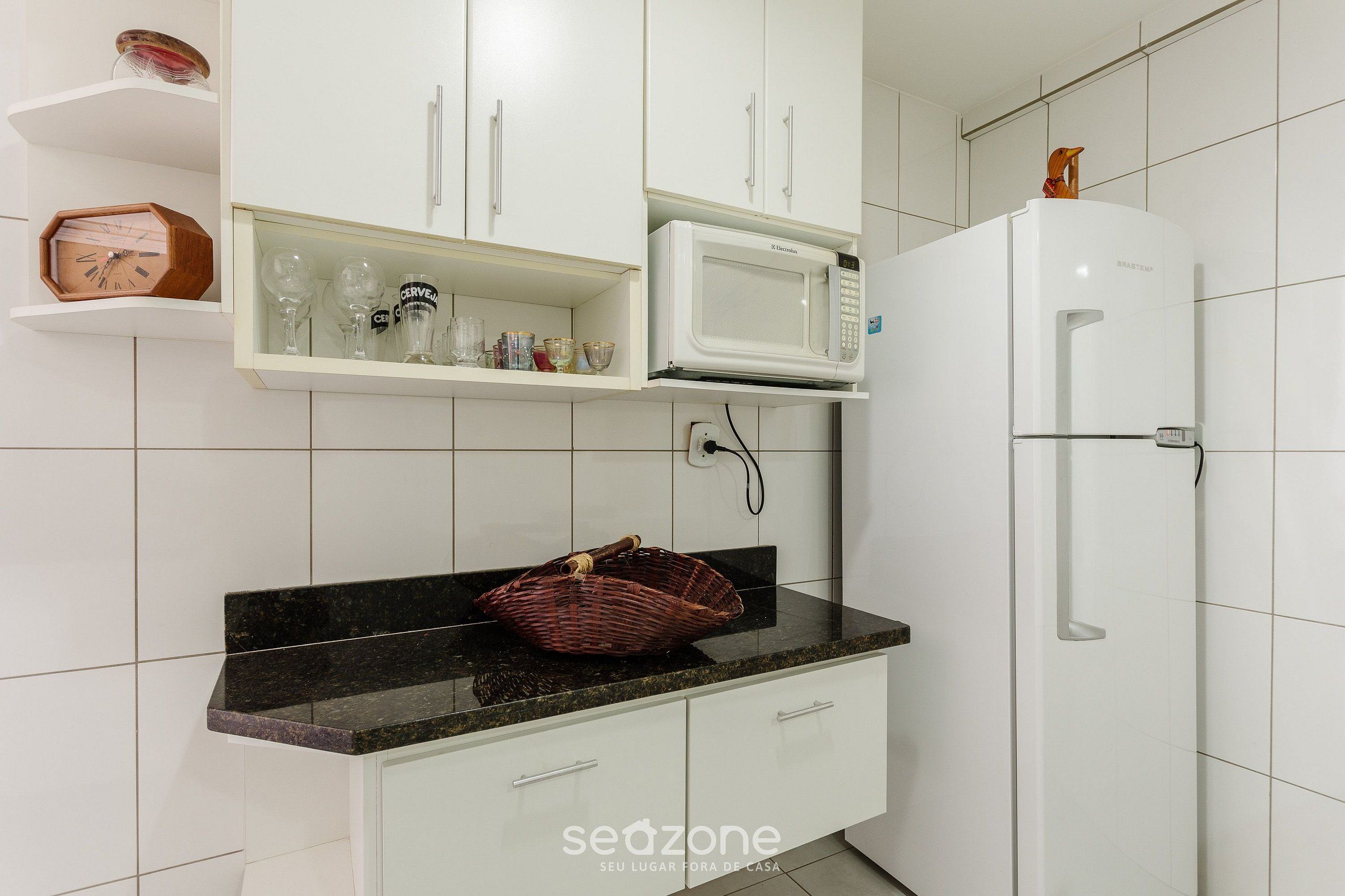 Una cocina con armarios blancos, un microondas y un refrigerador.