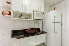Une cuisine avec des meubles blancs, un four à micro-ondes et un réfrigérateur.