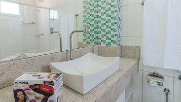 A bathroom with a white vessel sink, a mirror, a shower, and a tiled wall.