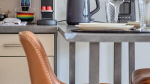 A modern kitchen with a brown leather chair, a kettle, and a coffee maker on the counter. - Célestine, mignon F2 en centre ville de Rouen - Proximité Donjon de Rouen (Rouen)