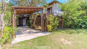 A wooden pergola leading to a white building with a dark door. - House, Beach, and Nature in Ibiraquera Tan0000 (Imbituba)
