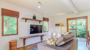 A living room with a television, wooden shelves, a bench, and a sofa with cushions. - House, Beach, and Nature in Ibiraquera Tan0000 (Imbituba)