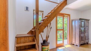 A wooden staircase leading to a room with a large window, a wooden cabinet, and a vase with sticks. - House, Beach, and Nature in Ibiraquera Tan0000 (Imbituba)