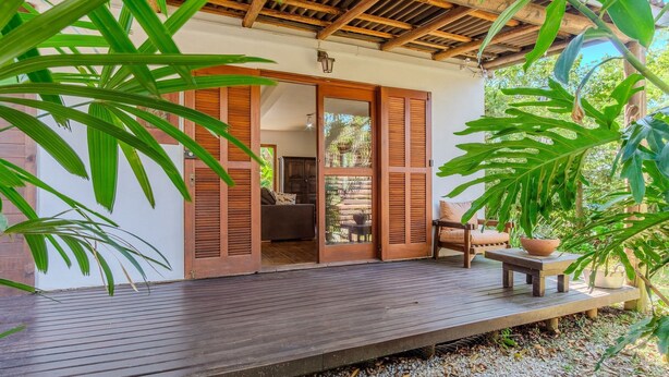A wooden deck with a view of a room with sliding doors and a sofa. - House, Beach, and Nature in Ibiraquera Tan0000 (Imbituba)