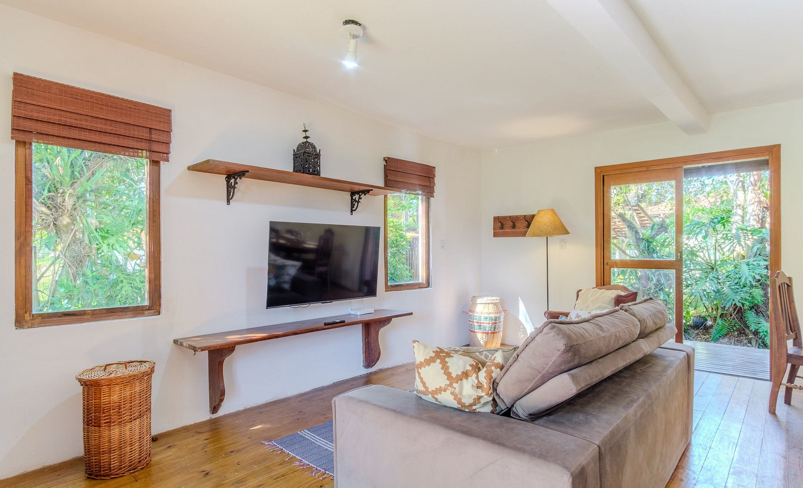 A living room with a television, wooden shelves, a bench, and a sofa with cushions.