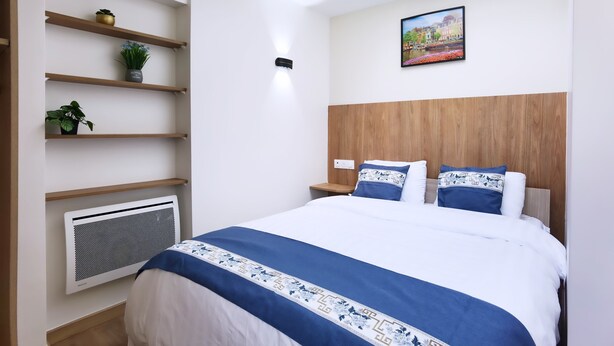 Un dormitorio moderno con cama, tragaluz, calefactor de pared y una pintura de paisaje urbano.