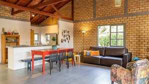 A spacious living area with a dining table, a sofa, and a patterned armchair.