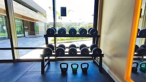 Un gimnasio con una estantería de mancuernas y kettlebells.
