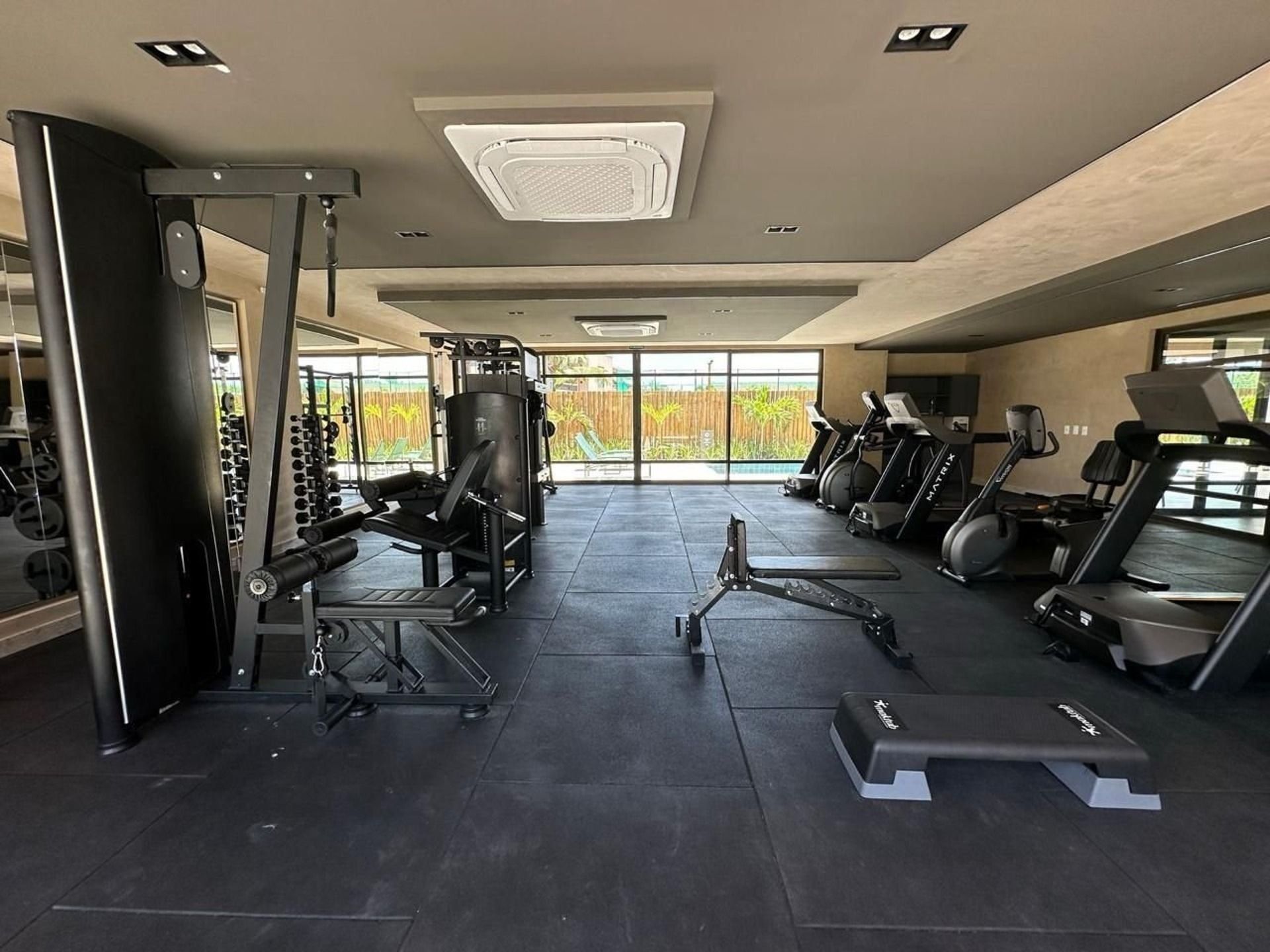 Une salle de sport équipée de divers appareils d’exercice, notamment des tapis de course, des appareils de musculation et des poids libres.
