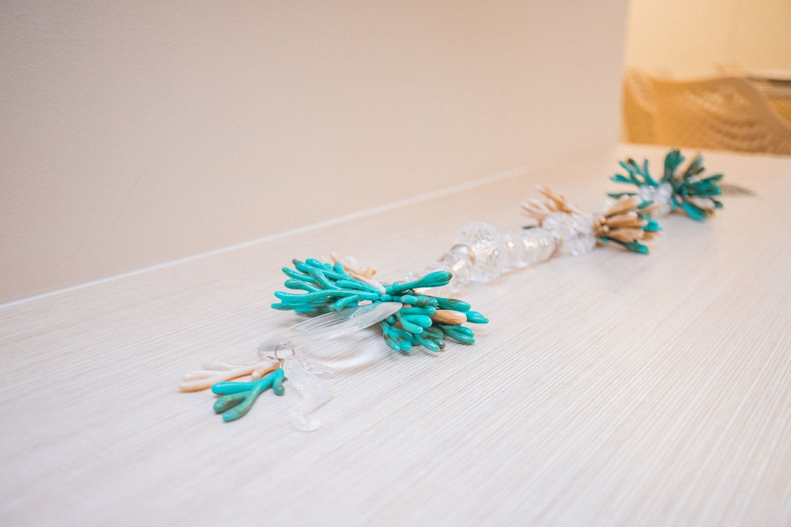 A decorative arrangement of glass ornaments and green foliage on a wooden surface.