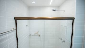 Una ducha moderna con paredes de azulejos blancos, estructura de madera y cabezal de ducha de mano.
