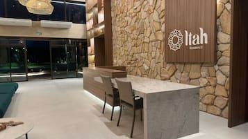 Un interior moderno con pared de piedra, mostrador de recepción y zona de estar.