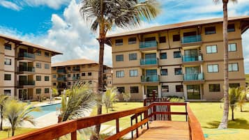 Un resort con edificios de varios pisos, una terraza de madera y una piscina.