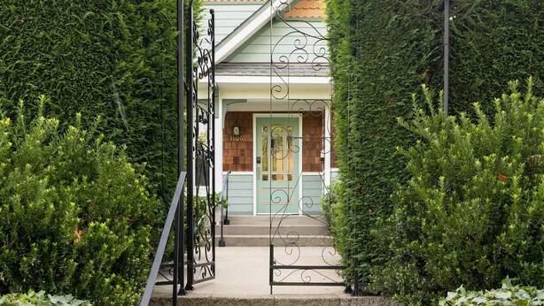 A set of stone steps leading to a house with a green door, surrounded by dense greenery. - Private Garden Home in Madison Valley (Seattle)