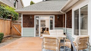 A wooden deck with wicker chairs and a patterned rug. - Private Garden Home in Madison Valley (Seattle)
