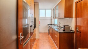 A compact kitchen with wooden cabinets, a built-in oven, and a microwave.
