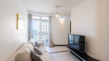 A modern living room with a sofa, TV, and a balcony view.