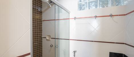 Un baño con cabina de ducha de vidrio, inodoro y lavamanos.