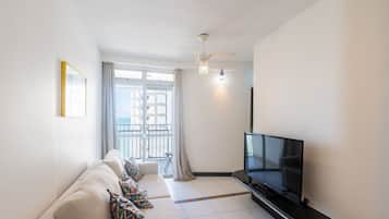 A modern living room with a sofa, TV, and a balcony view.