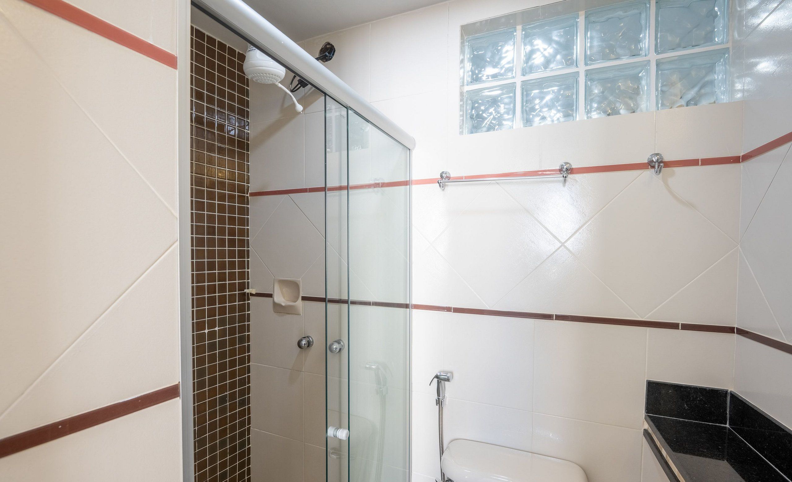 A bathroom with a glass shower enclosure, a toilet, and a sink.