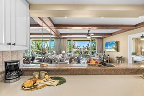 A modern kitchen with a coffee maker, fruit bowl, and dining area with a view of the outdoors.